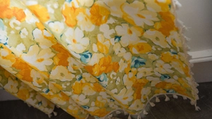 Close-up of yellow floral print curtain fabric featuring delicate white fringe tassels
