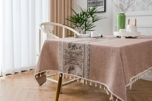 Detail of oatmeal linen table runner with brown Chinese pattern and white tassel trim