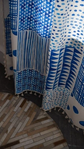 Detail eines Vorhangs im Boho-Stil mit blauen geometrischen Mustern und Quasten