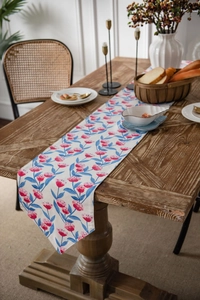 Floral table runner with pink flowers and blue leaves on a rustic wooden dining table