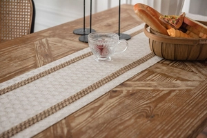 Macro shot of striped cotton linen table runner with fringes on a rustic wooden dining table