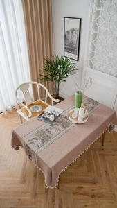 Detailed close-up of Chinese landscape printing and white tassel edges on a soft pink table runner