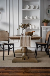 Close-up of dual-tone woven table runner with fringe on a rustic solid wood dining table