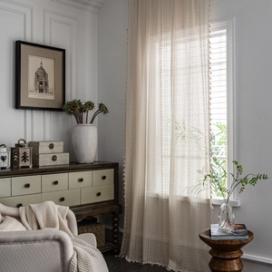 Beige crochet hollow lace curtains with fringe pom-poms for a rustic living room decor