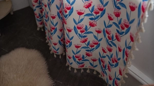 Detail von Vorhängen mit Tulpenmuster und beigen Quasten auf Baumwoll-Leinen-Stoff