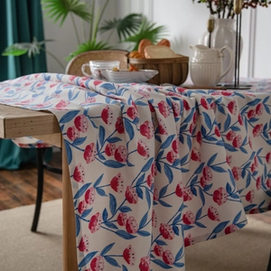 Floral cotton linen tablecloth with pink buds and blue leaves on a wooden dining table