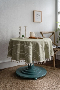 Détail de nappe tissée verte avec motifs de vagues blanches et franges de glands