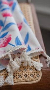 Detail eines geblümten Vorhangs mit rosa Blumen, blauen Blättern und Baumwollquasten