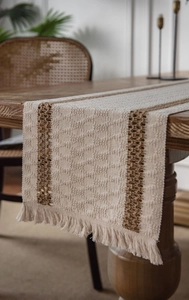 Close-up of bohemian table runner with beige woven texture, brown stripes and tassels