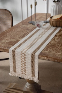 Close-up of Bohemian cotton linen table runner with woven tassels on a wooden table