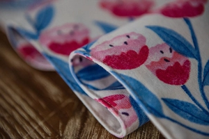 Detail of pink tulip floral print on thick cotton fabric with fine hemmed edges