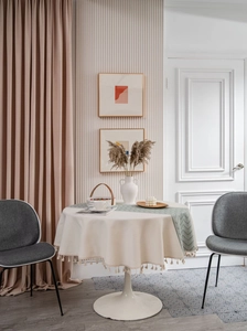 Detail of beige round tablecloth and cyan geometric runner with elegant fringe tassels