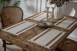 Detailed view of woven table mat with dark brown stripes and decorative tassel edges