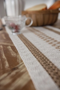 Macro view showing textured weave and brown striped patterns on cotton linen table runner