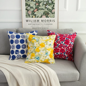 Detail of three decorative square pillow covers with floral and geometric patterns on a sofa