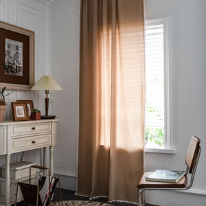Neutral solid color blackout curtain with decorative white pom-poms for a bohemian look