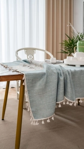 Detailed texture of blue-green table runner with elegant white tassels and geometric patterns