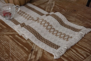 Close-up of cotton linen table runner with woven geometric patterns and rustic tassels