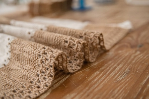 Close-up detail of rustic jute table runner featuring natural fiber texture and white lace trim