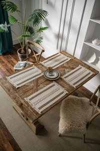 Detail of bohemian woven placemats with brown stripes and decorative fringes