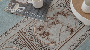Close-up of Chinese style blue table runner with brown magpie embroidery and geometric patterns