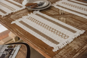 Close-up of woven cotton linen placemat with tassels and geometric patterns on a wooden table