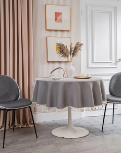 Detail of grey round tablecloth featuring bohemian white tassel fringe and jacquard texture