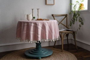 Détail de nappe ronde rose à texture losange avec pompons en coton blanc au style bohème