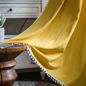 Ginger yellow linen curtain with white pom-poms for a minimalist Nordic home decor