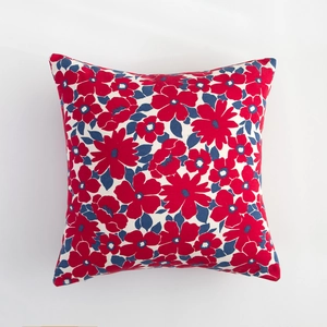 Detail of floral throw pillow cover with vintage red and blue blossoms on cream fabric