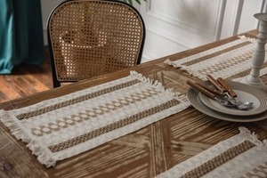 Detail of bohemian striped table mat with tassels on a rustic wooden dining table