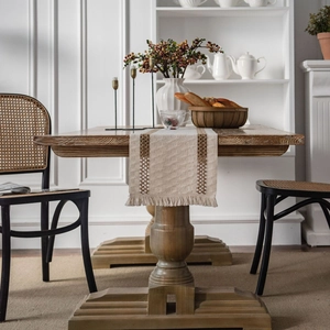 Linen table runner with woven geometric stripes and fringe on a dark wood table