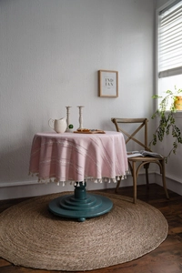 Gros plan d'une nappe ronde rose avec texture tissée et bordures à glands décoratifs