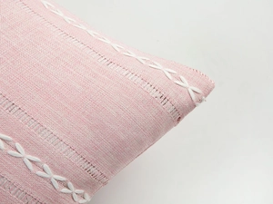 Detailed macro view of pink striped embroidered cushion cover with boho fringe lace