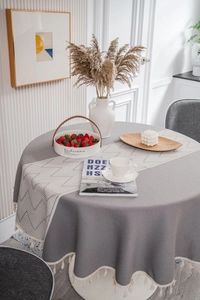 Close-up of a round grey tablecloth with decorative tassels and a geometric runner
