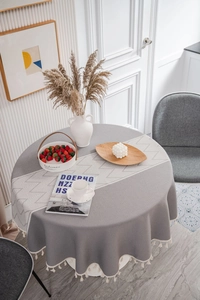 Detail of round grey tablecloth with white geometric patterns and tassel fringe edge