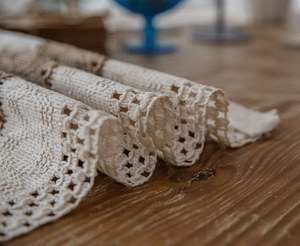 Detailed macro view of beige cotton woven table runner with intricate crochet lace borders