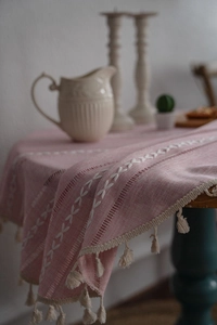 Détail de nappe en lin rose avec broderie de feuilles blanches et bords à franges