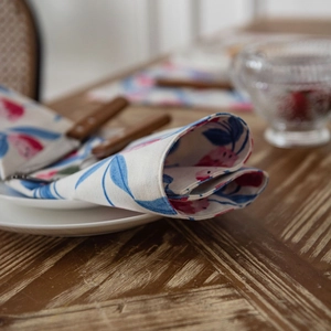 Floral table runner with pink flowers and blue leaves on a rustic wooden dining table
