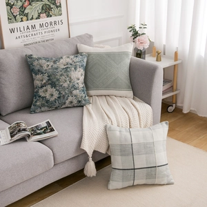 Close-up of geometric plaid and floral cushions with boho tassels on grey sofa