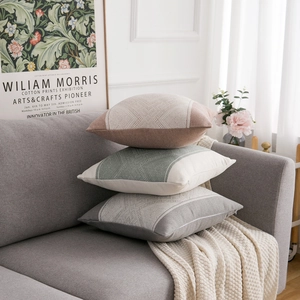 Close-up of geometric knit cushion covers in pink, green, and grey on a sofa