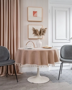 Detail of round beige jacquard tablecloth with elegant white tassel fringe and drapes