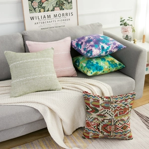 Set of five decorative striped and tie-dye bohemian pillow covers on a cozy sofa