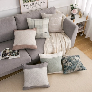 Collection of modern geometric cushion covers in mocha and cream tones on a sofa
