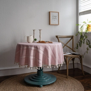 Nappe ronde rose avec broderie blanche, rayures et franges dans un décor chaleureux