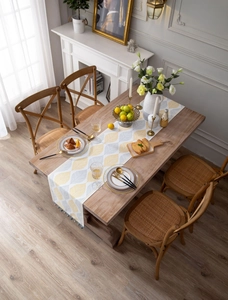 Overhead view of jacquard table runner with yellow leaf patterns and blue tassels