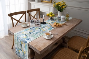 Detail of green and blue jacquard table runner with geometric fish patterns and tassels