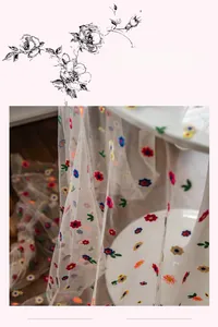 Detailed macro view of colorful floral embroidery on transparent white tulle lace fabric