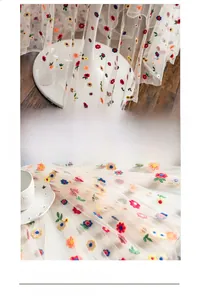Close-up of colorful floral embroidery on semi-transparent lace fabric with soft texture