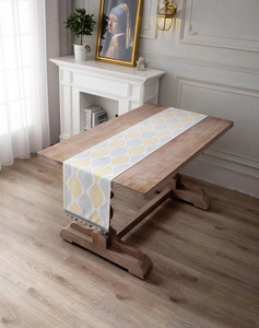 Detail of jacquard table runner featuring yellow leaf patterns and beaded tassels